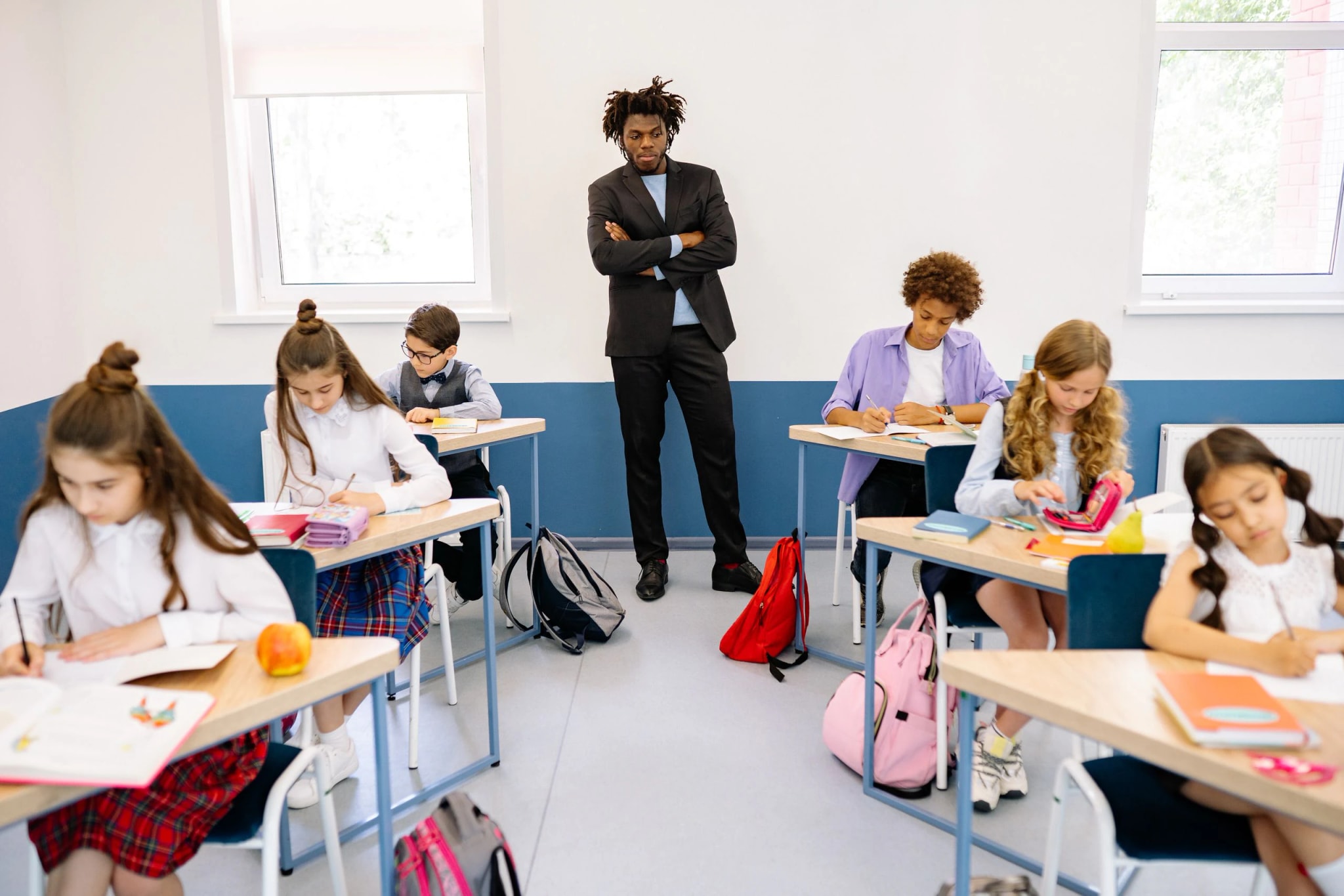 A teacher standing at the back of a classroom of students.