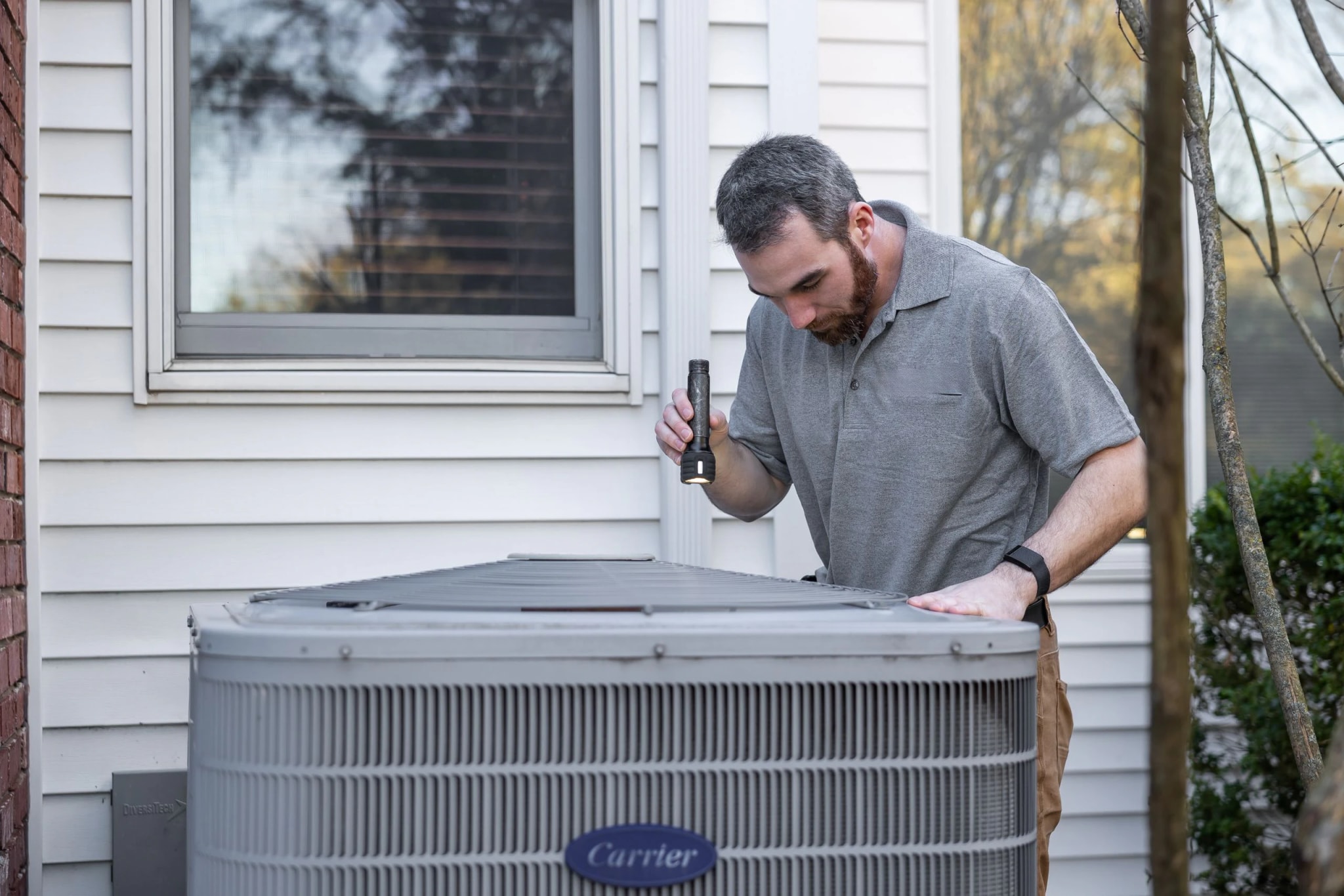 A technician inspecting an outdoor air conditioning unit.