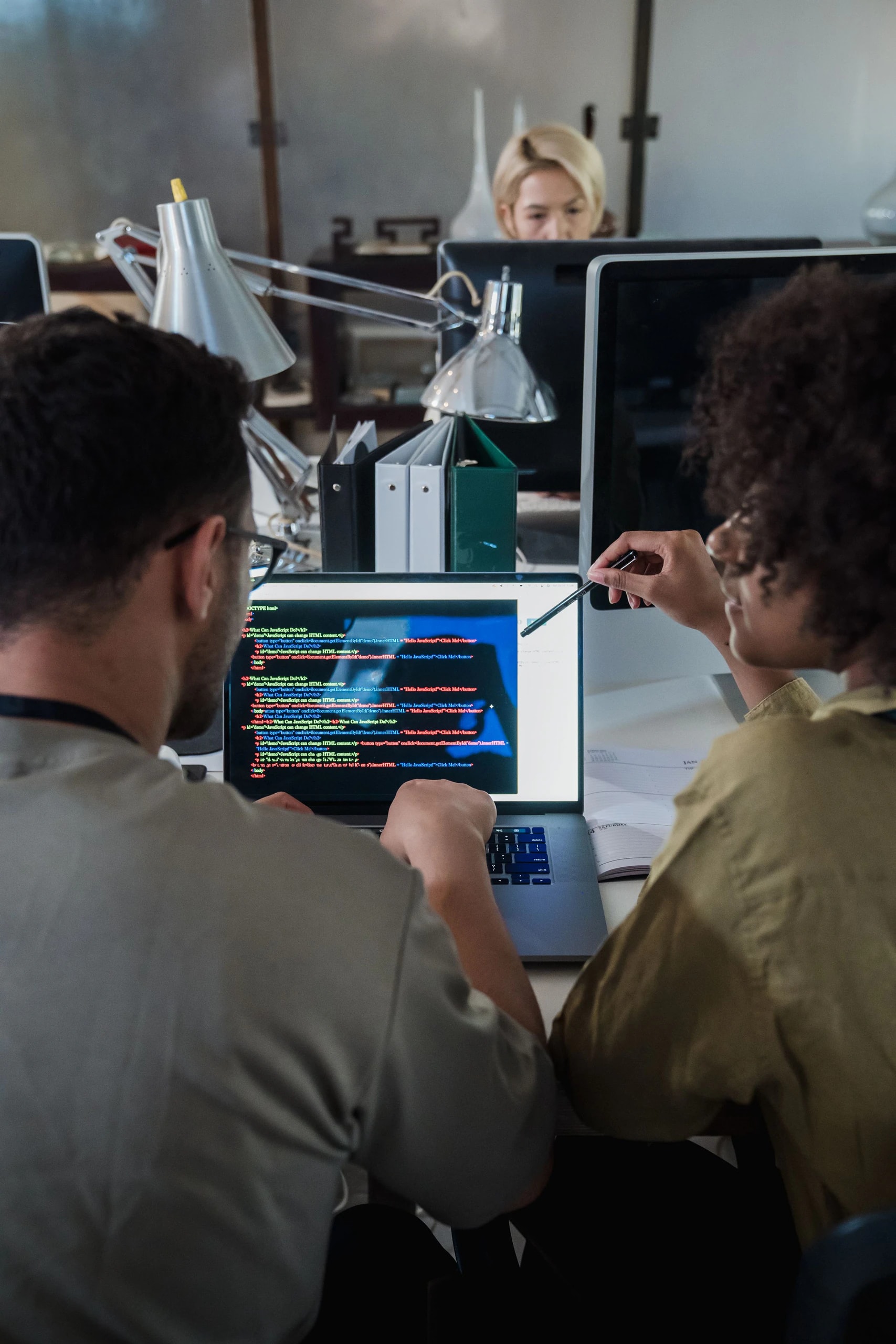 Two developers reviewing code together on a laptop.